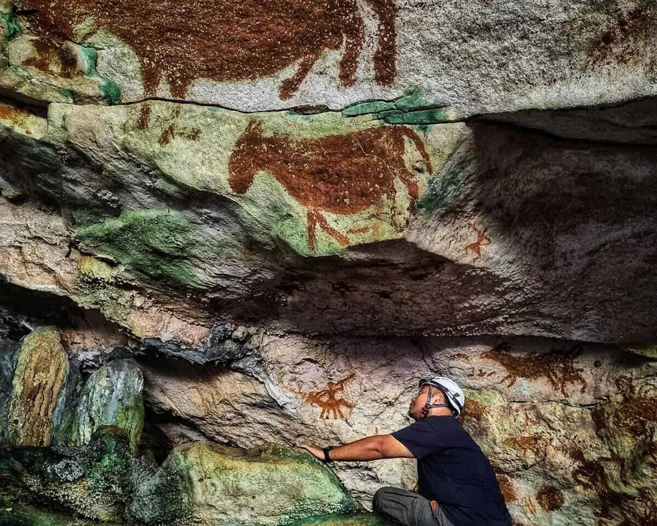BBC: This image provided by Maxime Aubert shows scientist Shinatria Adhityatama studying cave art found in Sulawesi, Indonesia. Maxime Aubert via AP